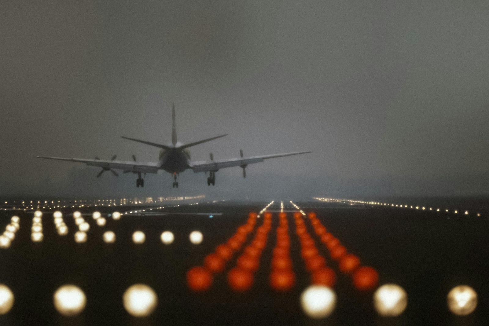 Runway lights and a landing aircraft in fog